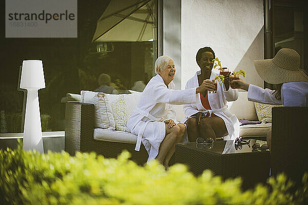 Glückliche ältere Frauen Freunde trinken Bloody Mary Cocktails auf der Terrasse