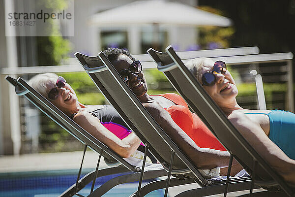 Porträt sorglos Senior Frauen Freunde Sonnenbaden am sonnigen poolside