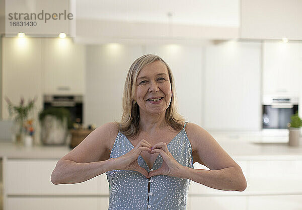 Porträt schöne glückliche ältere Frau gestikulieren Herzform in der Küche