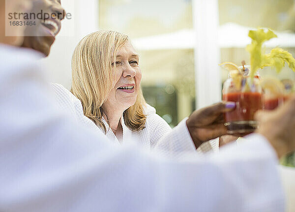 Glückliche Seniorin genießt Bloody-Mary-Cocktail mit Freunden