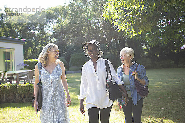 Glückliche ältere Frauen Freunde zu Fuß in sonnigen Sommergarten