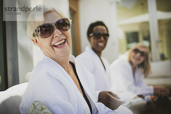 Porträt glückliche ältere Frau im Spa-Bademantel lachend auf der Terrasse