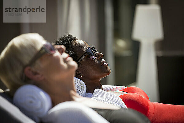 Serene ältere Frauen Freunde Sonnenbaden in Sonnenbrille auf sonnigen Terrasse