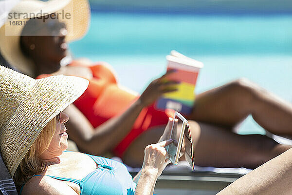 Senior Frau mit Smartphone und Sonnenbaden am Sommer-Pool