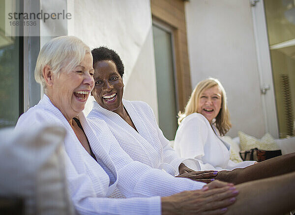 Glückliche Frauen Freunde in Spa-Bademäntel lachen auf der Terrasse