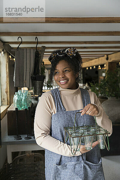 Porträt glückliche weibliche Ladenbesitzerin hält Glas Pflanzenhalter