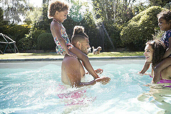 Familie spielt im sonnigen Sommer Schwimmbad