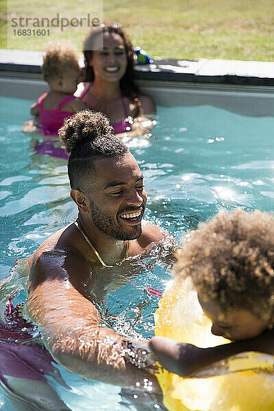 Glückliche Familie spielen in sonnigen Sommer Schwimmbad