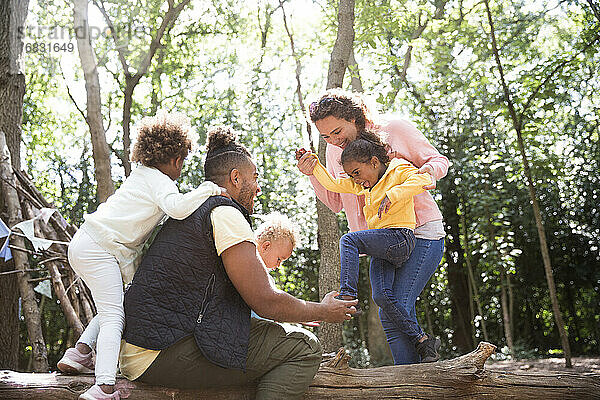 Glückliche Familie spielen auf gefallenen Stamm im Sommer Wald