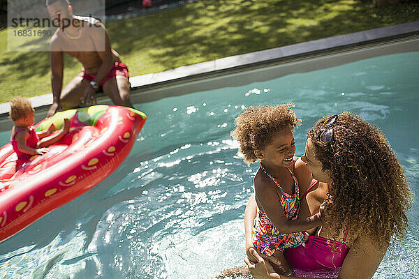 Familie spielt im sonnigen Sommer Schwimmbad