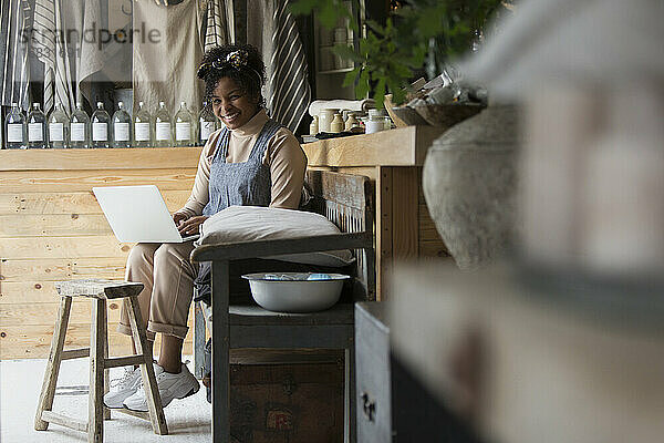 Porträt glückliche weibliche Ladenbesitzerin mit Laptop in Haushaltswarengeschäft