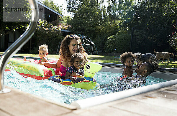 Glückliche Familie spielen in sonnigen Sommer Schwimmbad