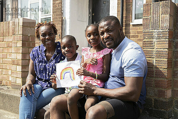 Porträt glückliche Familie mit Regenbogen Zeichnung auf sonnigen vorderen stoop