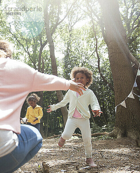 Mutter und Töchter spielen im sonnigen Sommer Wald