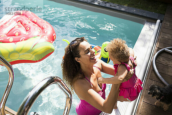 Glückliche Mutter hebt Tochter in sonnigen Sommer Schwimmbad