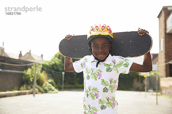 Porträt zuversichtlich Junge mit Skateboard in sonnigen Parkplatz
