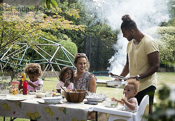 Glückliche Familie genießt Sommer Barbecue auf der Terrasse Tisch