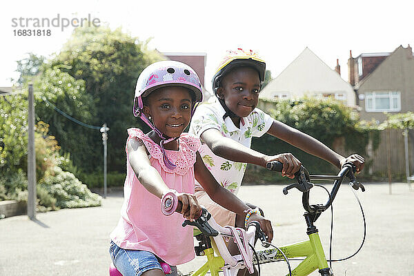 Porträt glücklich Bruder und Schwester Reiten Fahrräder in sonnigen Nachbarschaft