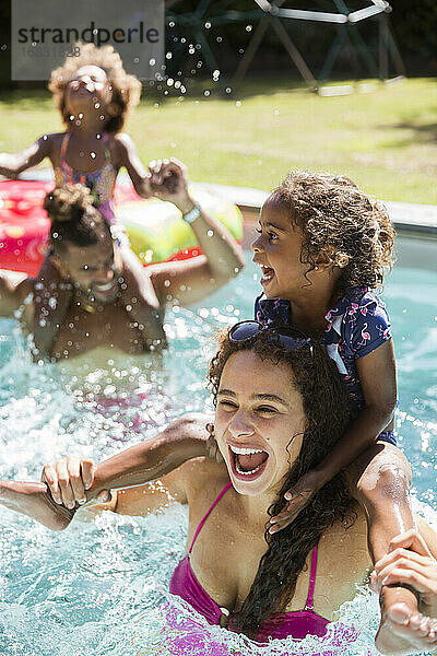 Glückliche spielerische Familie im sonnigen Sommer Schwimmbad