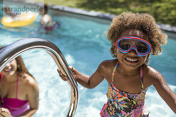 Porträt niedlichen Mädchen in Schwimmbrille am sonnigen Schwimmbad
