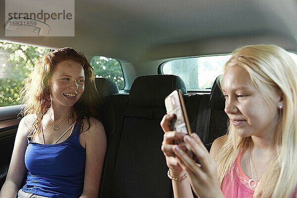 Preteen Mädchen Freunde mit Smartphone auf dem Rücksitz des Autos