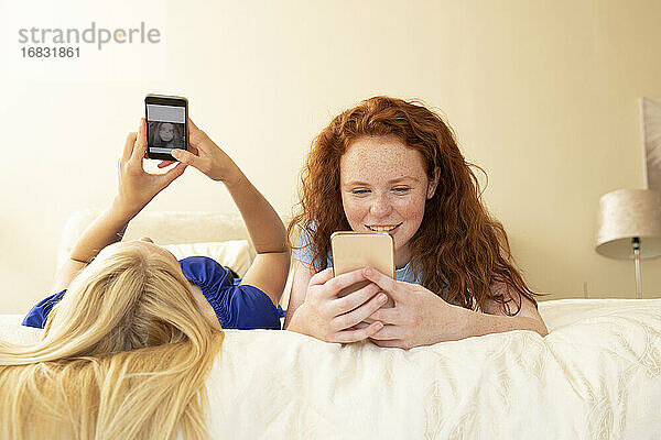 Preteen Mädchen Freunde mit Smartphones auf dem Bett