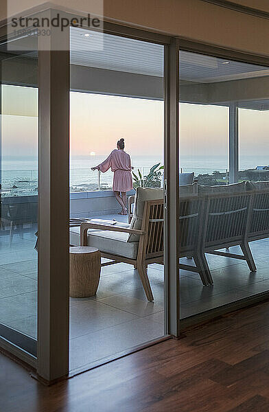 Frau genießt malerischen Sonnenuntergang Meerblick von Luxus-Balkon