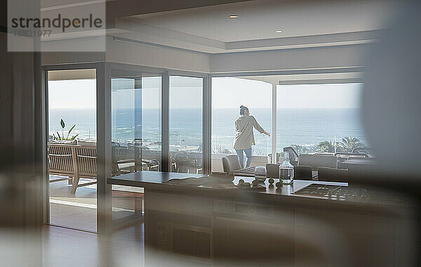 Frau mit Blick auf sonnigen Blick auf das Meer auf Luxus nach Hause Schaufenster Balkon