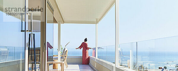 Frau in langen Kleid genießen sonnigen malerischen Meerblick auf Luxus-Balkon