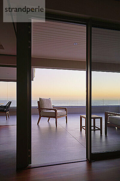 Sessel auf dem Balkon einer Luxuswohnung mit Blick auf den Sonnenuntergang am Meer