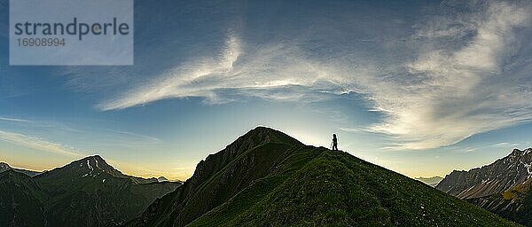 Bergsteiger auf Bergwiese des Habart Kammes im Vordergrund mit Bergen des Maldongrates im Hintergrund bei Sonnenaufgang  Elmen  Lechtaler Alpen  Außerfern  Tirol  Österreich  Europa