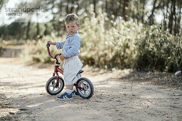 Kleinkind mit dem Laufrad auf Feldweg