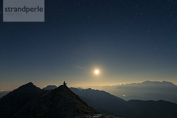 Bergsteiger auf Gipfelgrat mit Vollmond und Sternenhimmel  im Hintergrund Ammergauer Alpen  Reutte  Ammergauer Alpen  Tirol  Österreich  Europa