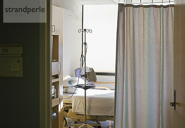 Krankenhauszimmer mit Bett und Sichtschutzvorhang.