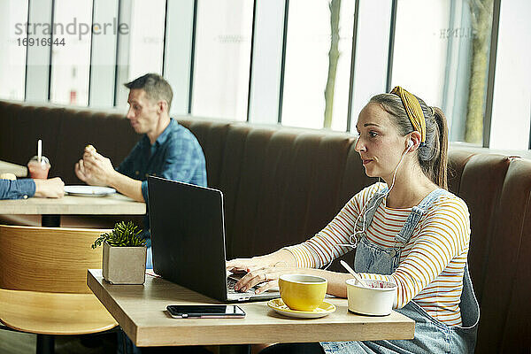 Frau in einem Café sitzend mit einem Laptop