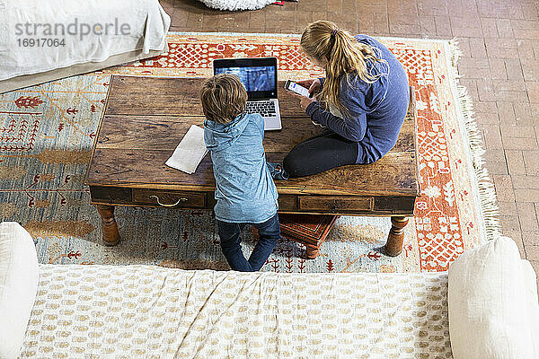 Overhead-Ansicht von Teenager-Mädchen und ihr jüngerer Bruder mit Laptop und Smartphone