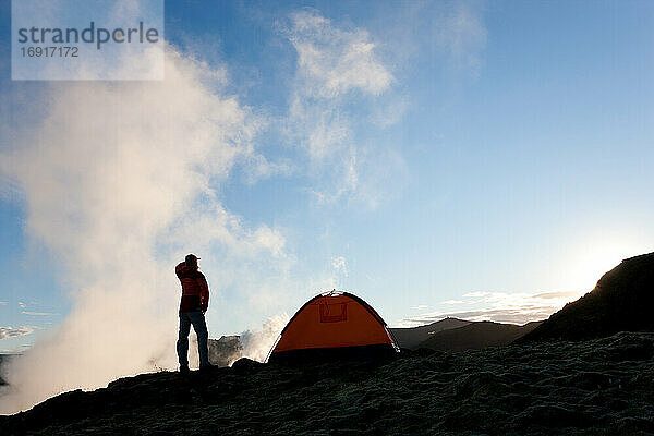 Frau stehend am Zelt bei Sonnenaufgang  Island