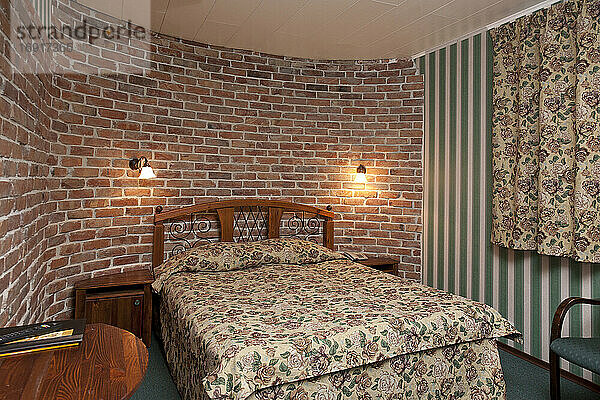 Bett im Schlafzimmer mit Tapete und Ziegelwand.