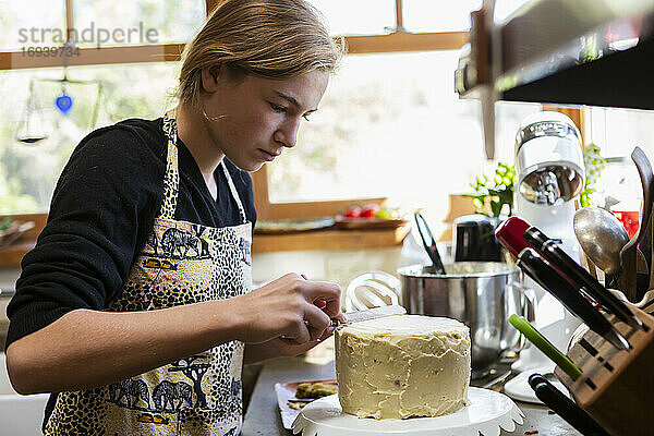 Teenager-Mädchen in der Küche Anwendung Zuckerguss auf Kuchen