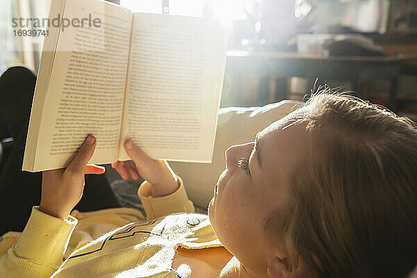 Teenager-Mädchen liest Buch zu Hause im frühen Morgenlicht