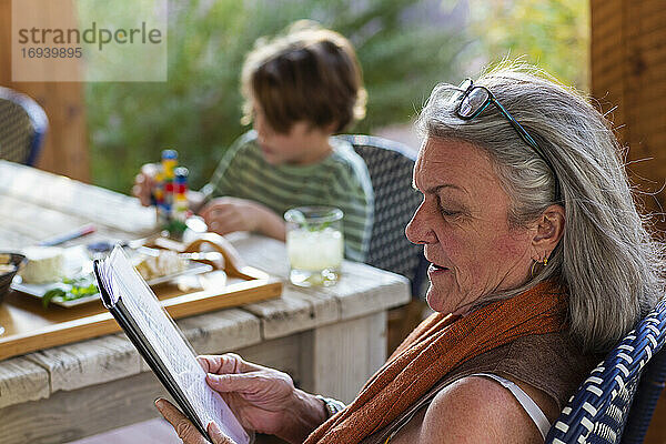 Frau liest Akte draußen auf Terrasse bei Sonnenuntergang.