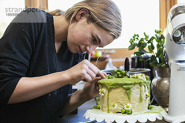 Teenager-Mädchen in der Küche Anwendung Zuckerguss auf Kuchen