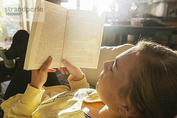 Teenager-Mädchen liest Buch zu Hause im frühen Morgenlicht