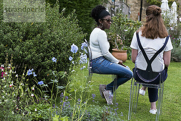 Frau und weiblicher Therapeut im Gespräch in einem Garten.