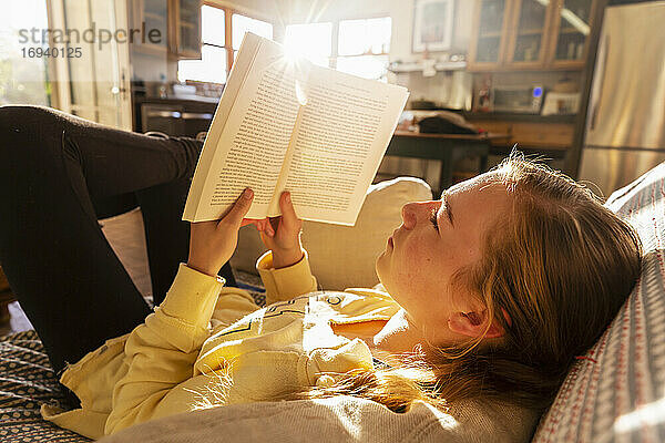 Teenager-Mädchen liest Buch zu Hause im frühen Morgenlicht