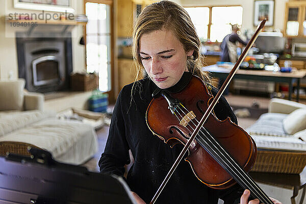 Teenager-Mädchen übt Geige zu Hause