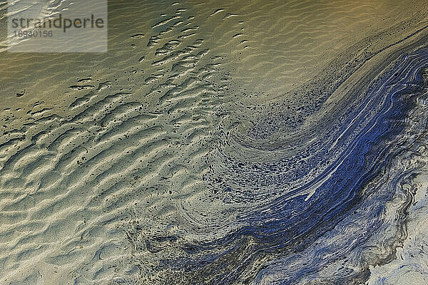 Meerwasser und Wellenmuster im Sand bei Ebbe.