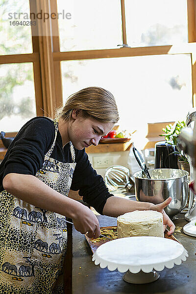 Teenager-Mädchen in der Küche Anwendung Zuckerguss auf Kuchen