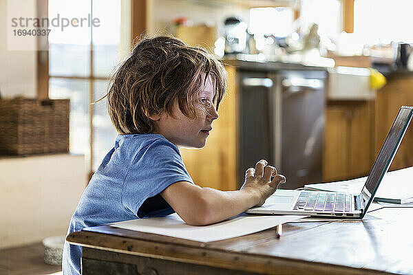 Junger Junge mit seinem Laptop-Computer zu Hause