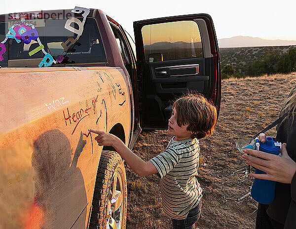 Zwei Kinder malen die Seite eines alten Pickup-Trucks